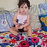 toddler, child, baby, sitting, couch, blanket, pillow, colorful, floral, clothing, socks, face, hair, indoor, cute, portrait, person, expression, home, cozy