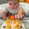 baby, birthday_cake, blueberry, cake, candle, celebration, child, cream, cute, face, fingers, fruit, hand, indoor, mango, number_6, plush_pillow, sitting, soft_lighting, star_candle