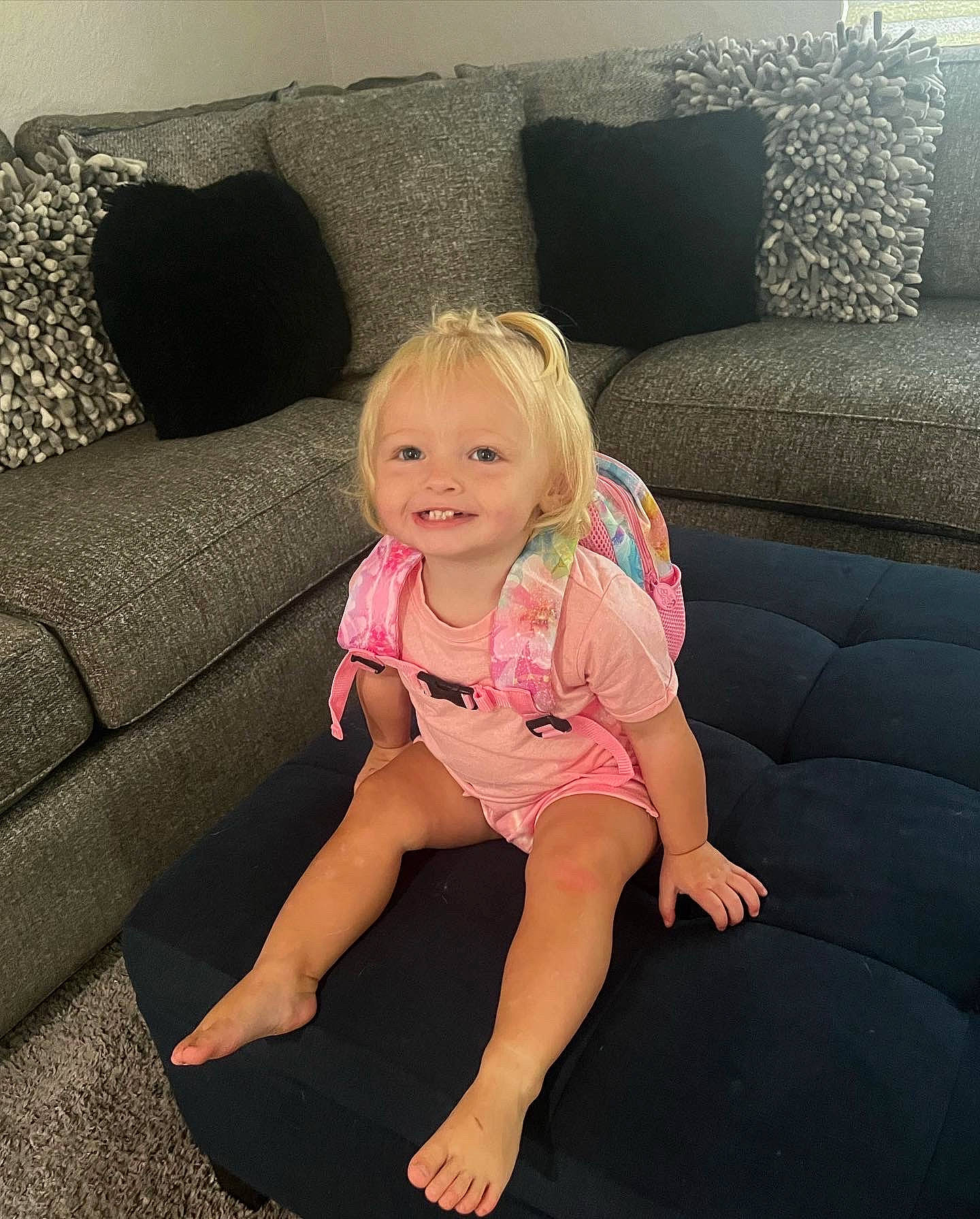 Miyah joined the competition — help win amazing prizes! baby_toddler_clothing, comfort, couch, eye, face, floor, flooring, foot, furniture, hair, head, human_leg, joy, knee, leg, living_room, person, smile, studio_couch, textile
