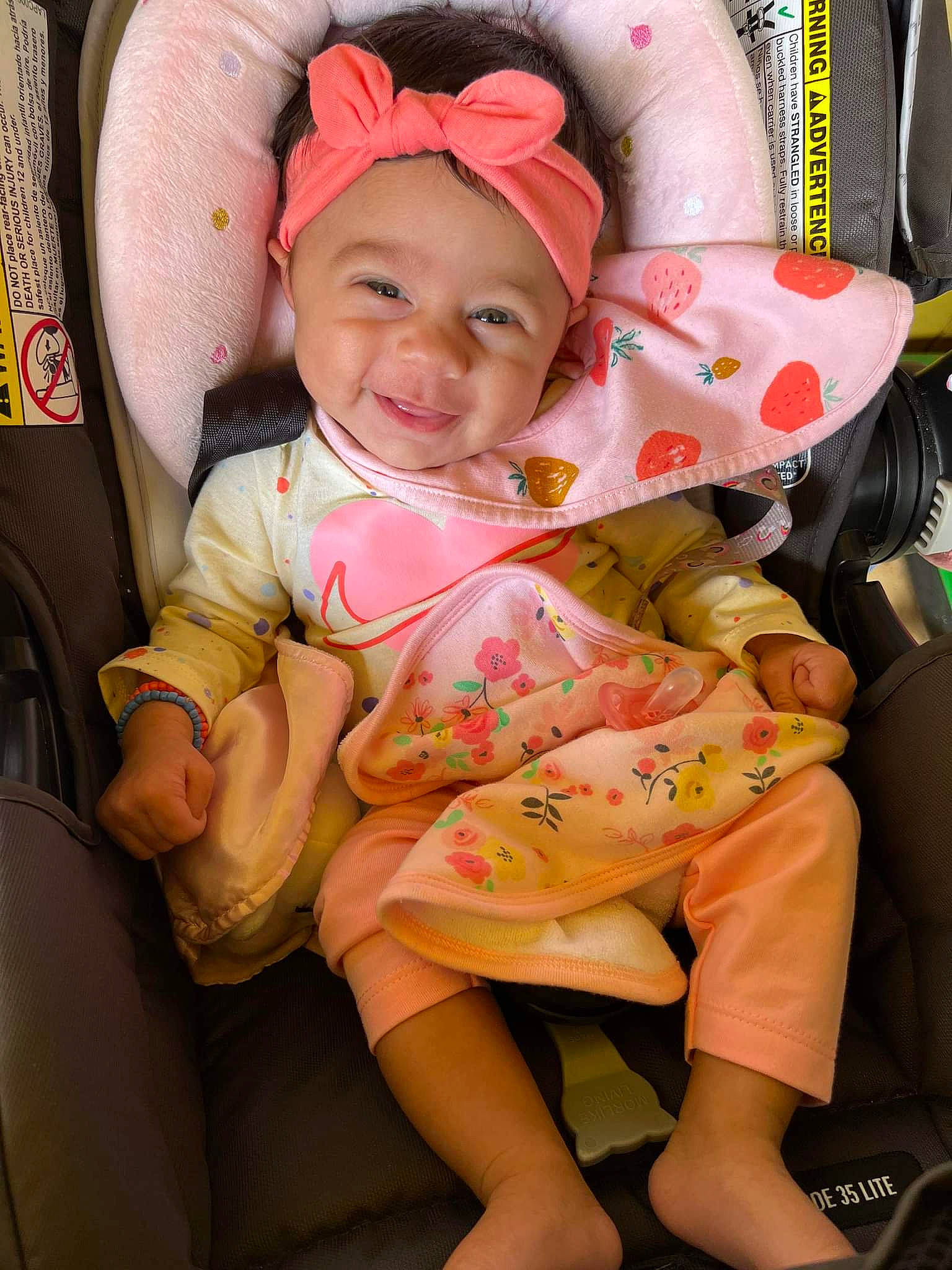 India is registered to the contest to win money with this photo: baby, baby_carriage, baby_toddler_clothing, car_seat, child, comfort, fun, happy, headwear, human_leg, lap, leg, mouth, person, pink, skin, sleeve, smile, thigh, thumb