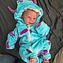 baby, infant, costume, monster, blue, purple, hood, smiling, cute, feet, bed, blanket, soft, child, person, clothing, happy, lying_down, indoor, portrait
