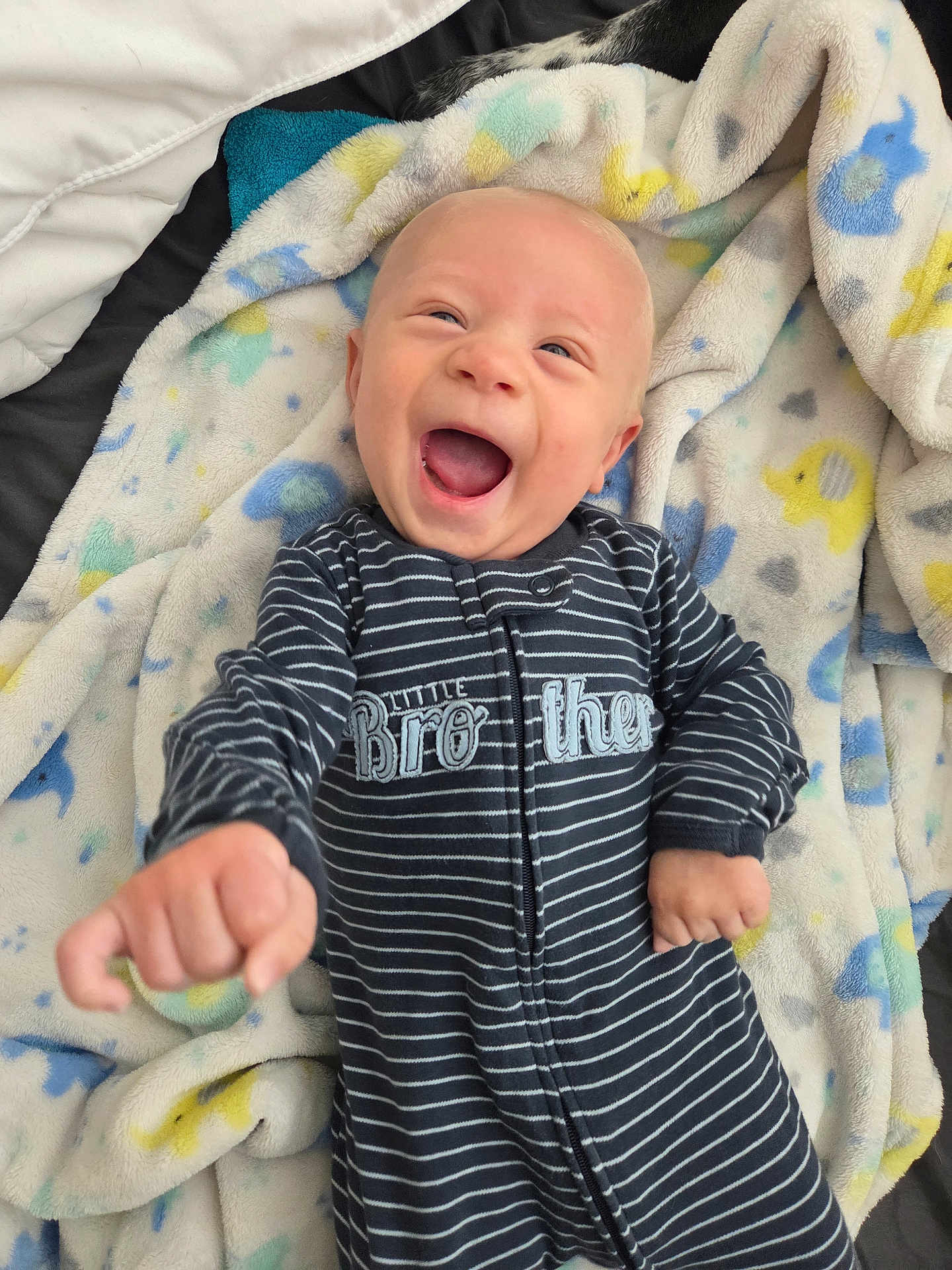 Ares is registered to the contest to win money with this photo: baby, infant, smiling, laughing, striped_clothing, onesie, blanket, elephant_pattern, soft_texture, lying_down, happy, joyful, child, cute, portrait, indoor, person, young_child, sleepsuit, cozy