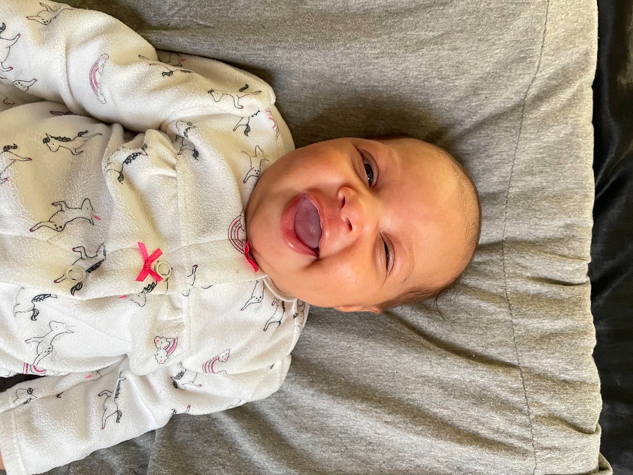 Rhea is registered to the contest to win money with this photo: arm, baby, baby_laughing, baby_products, baby_toddler_clothing, cheek, child, comfort, eye, face, happy, head, linens, lip, mouth, nose, person, skin, sleeve, smile