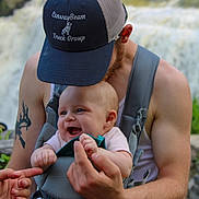 Maylynn joined the competition — help win amazing prizes! baby, man, hat, tattoo, baby_carrier, smile, happy, outdoor, nature, waterfall, person, arm, holding, clothing, headwear, beard, skin, portrait, child, family