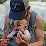 baby, man, hat, tattoo, baby_carrier, smile, happy, outdoor, nature, waterfall, person, arm, holding, clothing, headwear, beard, skin, portrait, child, family