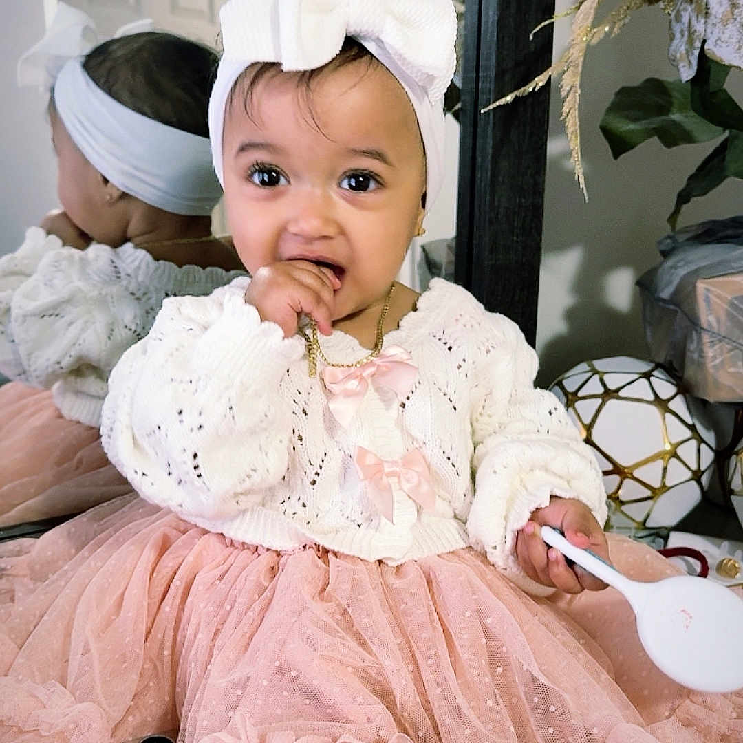 Nasya Ellie joined the competition — help win amazing prizes! baby, child, toddler, portrait, smiling, indoor, dress, tutu, pink, white, bow, headband, spoon, mirror, reflection, sitting, fashion, nursery, flower_arrangement, furniture