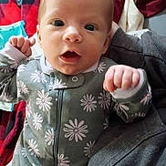 Khaos joined the competition — help win amazing prizes! baby, newborn, infant, onesie, daisy_pattern, face, closeup, eyes, hands, fists, portrait, indoor, blanket, bedding, remote_control, clothing, expression, skin, head, lying_down