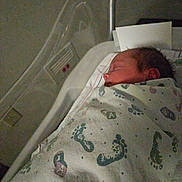 James joined the competition — help win amazing prizes! newborn, baby, swaddled, hospital_bassinet, blanket, footprints, sleeping, infant, side_view, hospital, bed, head, person, portrait, peaceful, indoors, medical, resting, cute, young_child