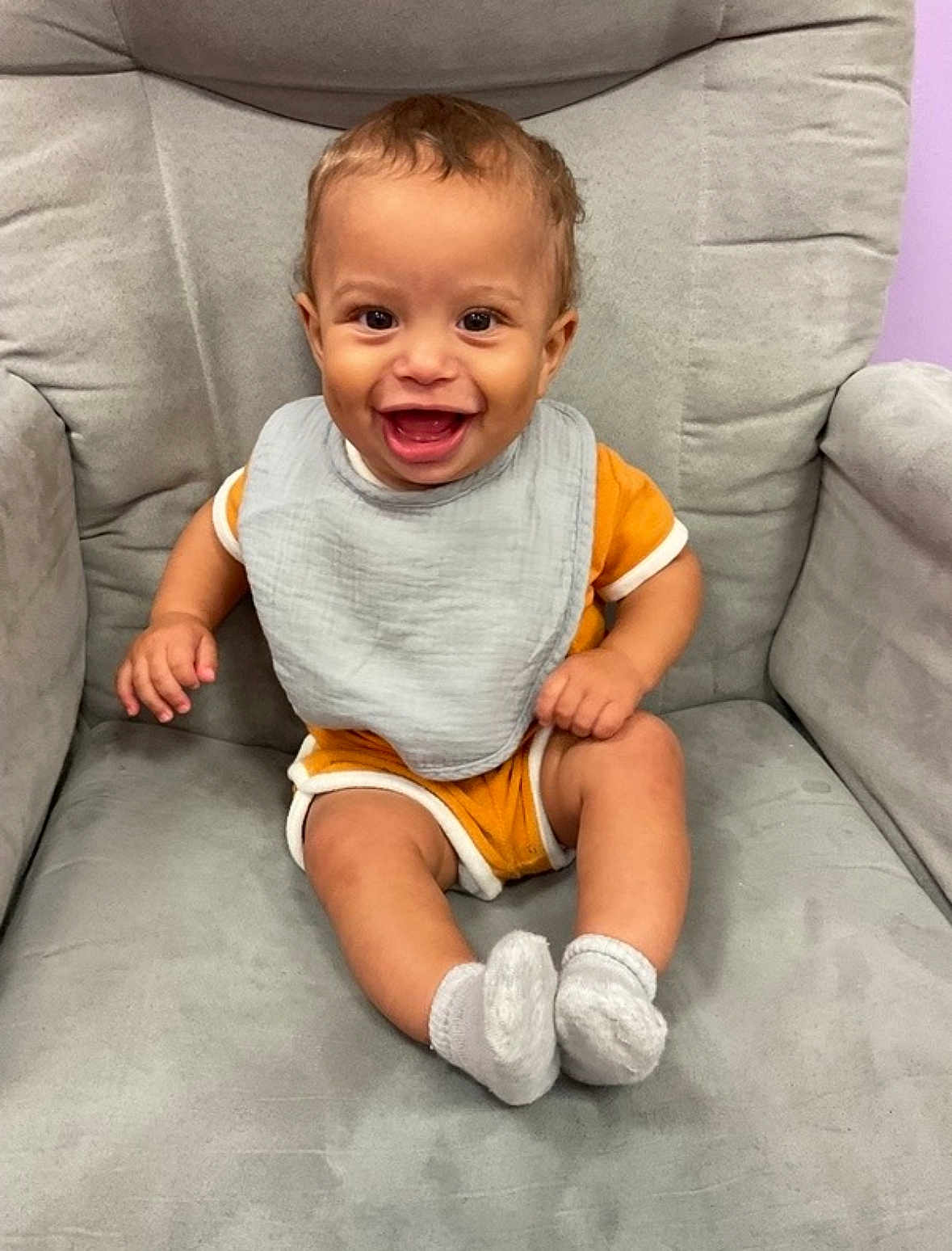 Jasper joined the competition — help win amazing prizes! baby, child, smiling, bib, orange_outfit, gray_chair, socks, happy, indoor, infant, cute, portrait, seated, one_person, young_child, short_hair, skin, face, expression, furniture