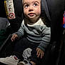 toddler, child, car_seat, sweater, white_shoes, plush_toy, curious, indoor, seat_belt, baby, footwear, clothing, portrait, small_hands, looking_up, cute, casual_wear, child_safety, infant, soft_lighting