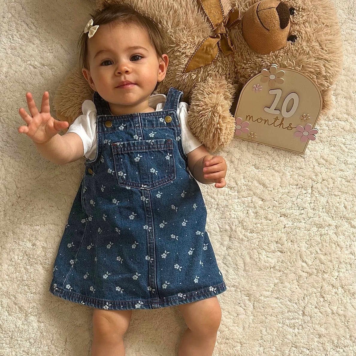 Giulia participe au concours pour gagner de l'argent avec cette photo : baby, bow, carpet, child, cozy, curious, cute, denim_dress, floral_pattern, indoor, laying_down, milestone_sign, plush, portrait, reaching_out, smiling, soft_texture, stuffed_animal, teddy_bear, toddler