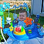 baby, child, smiling, outdoor, grass, toy, activity_jumper, play, colorful, blue, orange, green, plastic, happy, infant, sunlight, face, clothing, person, garden