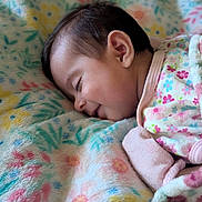 Aurora is registered to the contest to win money with this photo: baby, blanket, child, closeup, clothing, comfort, cozy, cute, face, floral_pattern, head, indoors, infant, pastel_colors, peaceful, portrait, resting, sleeping, soft_texture, warmth