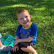 Donald joined the competition — help win amazing prizes! child, boy, smiling, grass, park, pizza, food, blue_shirt, red_hair, green_shoes, sunlight, outdoor, picnic, tree, leafy, casual_clothing, happy, sitting, daytime, nature