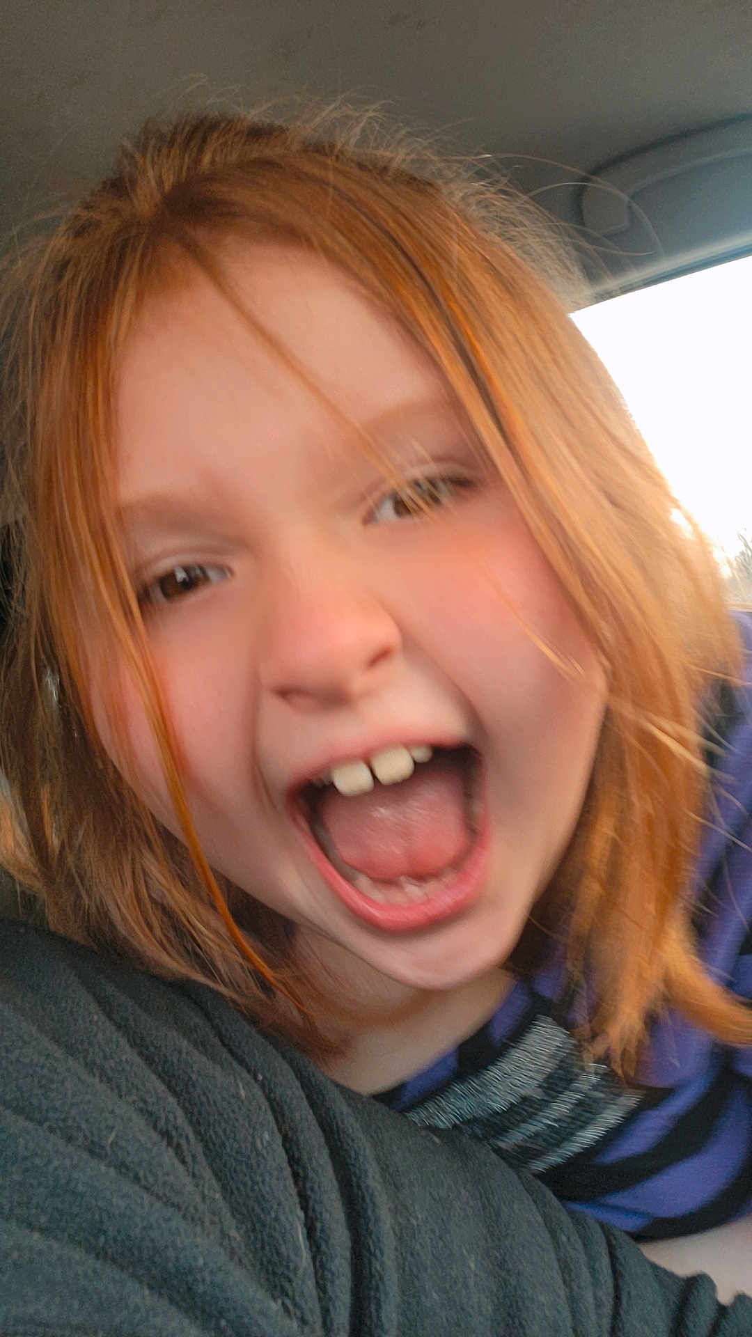 Brandy is registered to the contest to win money with this photo: child, red_hair, open_mouth, car_interior, close_up, joyful, happy, face, person, candid, mouth, teeth, hair, seat, window, clothing, portrait, emotion, excited, casual