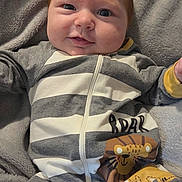 Jaxson joined the competition — help win amazing prizes! baby, infant, child, smiling, face, red_hair, onesie, striped_clothing, lion_print, blanket, soft_texture, cute, lying_down, indoors, closeup, portrait, happy, chubby_cheeks, zipped_clothing, playful
