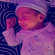 Alessio Belhache participe au concours pour gagner de l'argent avec cette photo : baby, bedtime, blanket, child, clothing, cute, face, hand, hat, indoors, infant, onesie, pattern, peaceful, portrait, resting, sleeping, smileys, soft_lighting, text_print