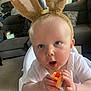 Adonis Joe is registered to the contest to win money with this photo: baby, child, bunny_ears, toy, high_chair, indoor, couch, cushion, curtains, carpet, person, white_clothing, plush, face, expression, hand, seat, furniture, cute, surprised