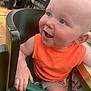 baby, child, high_chair, orange_clothing, smiling, happy, indoor, dining, table, seat, person, face, blue_eyes, shorts, crab_pattern, hand, skin, cute, young, infant