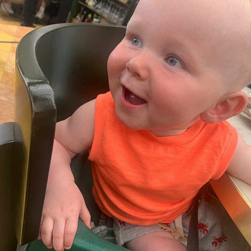 Adonis Joe joined the competition — help win amazing prizes! baby, blue_eyes, child, crab_pattern, cute, dining, face, hand, happy, high_chair, indoor, infant, orange_clothing, person, seat, shorts, skin, smiling, table, young
