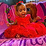 toddler, child, red_dress, bow, sitting, blanket, princess_theme, happy, indoors, curtains, window, smiling, feet, face, young_child, portrait, colorful, fabric, home, excited
