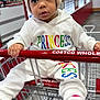 Esteisy joined the competition — help win amazing prizes! baby, child, shopping_cart, hat, knit_hat, white_clothing, socks, indoor, store, retail, curious, person, infant, colorful_text, face, eyes, hand, floor, metal, seated