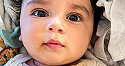 Raivy Alexander is registered to the contest to win money with this photo: baby, infant, face, eyes, curly_hair, blanket, clothing, onesie, cute, portrait, closeup, child, soft_texture, indoors, resting, expression, adorable, skin, light, young