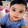 baby, child, face, smile, blue_shirt, striped_clothing, big_eyes, close_up, indoor, television, blurred_background, soft_surface, cute, portrait, person, infant, happy, skin, hair, lying_down