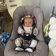 Thiago a rejoint le concours — aidez-le/la à gagner de superbes lots ! baby, infant, baby_seat, pacifier, knitted_outfit, lion_patch, straps, cushion, indoor, floor_tiles, chair, baby_shoes, baby_clothing, baby_toys, baby_care, person, face, baby_furniture, curious, safe