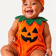 Lynx is registered to the contest to win money with this photo: baby, child, infant, pumpkin_costume, halloween, orange, bow, headband, smiling, laughing, portrait, studio, sitting, onesie, jack_o_lantern, leaf_collar, barefoot, happy, costume, photography
