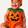 baby, child, infant, pumpkin_costume, halloween, orange, bow, headband, smiling, laughing, portrait, studio, sitting, onesie, jack_o_lantern, leaf_collar, barefoot, happy, costume, photography