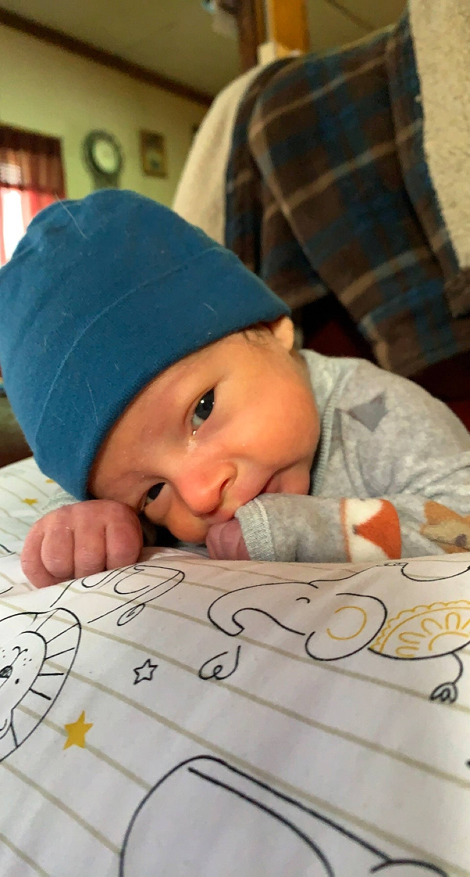 Gerald is registered to the contest to win money with this photo: baby, baby_toddler_clothing, cap, cheek, child, comfort, face, flooring, happy, head, headwear, knit_cap, outerwear, pattern, person, sitting, skin, smile, textile, toddler