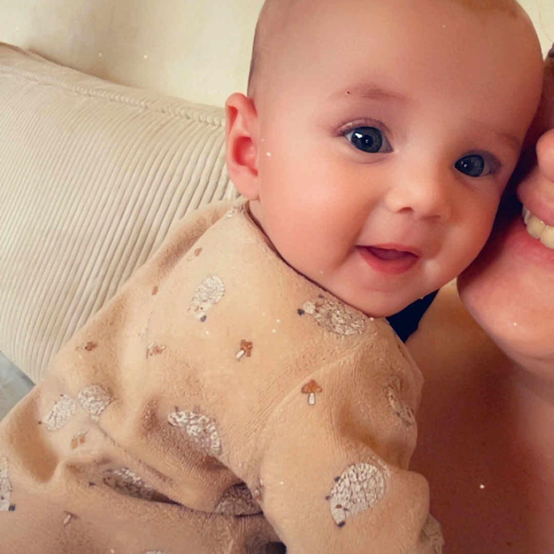 Inaya a rejoint le concours — aidez-le/la à gagner de superbes lots ! baby, beige, child, clothing, couch, cozy, cute, face, framed_picture, happy, hedgehog, indoor, infant, love, parent, pattern, person, portrait, smiling, wall