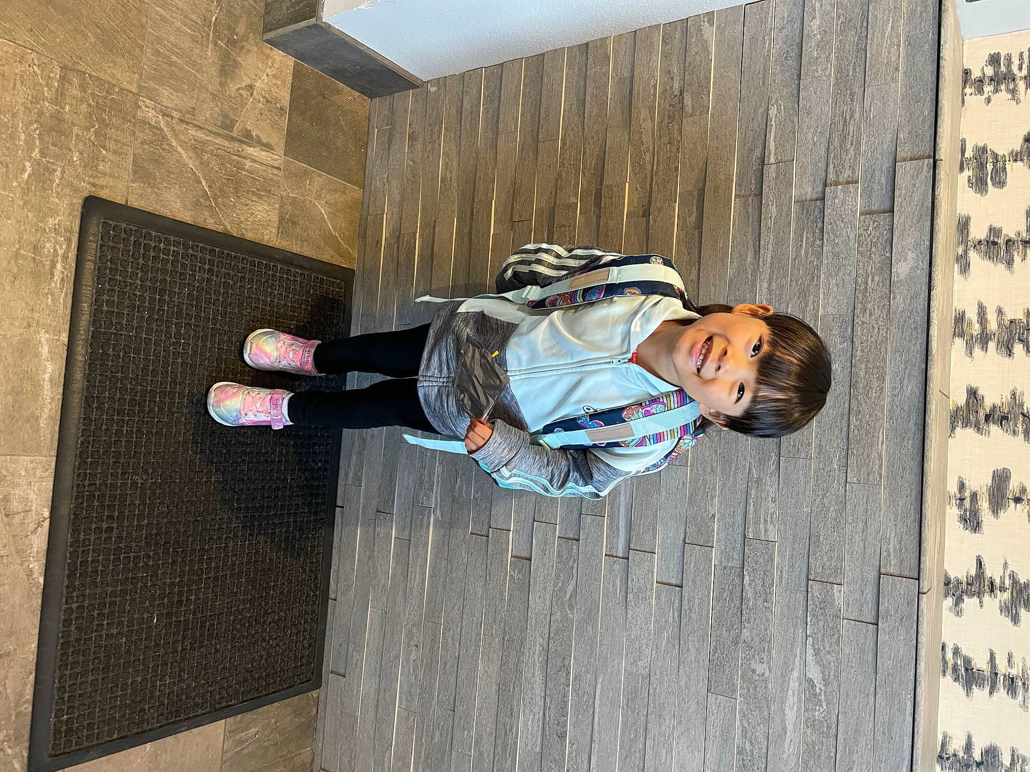 Mia is registered to the contest to win money with this photo: bag, child, concrete, denim, eyewear, facade, flooring, fun, happy, joy, leisure, outdoor_shoe, pedestrian, person, sitting, street, walking_shoe, wood