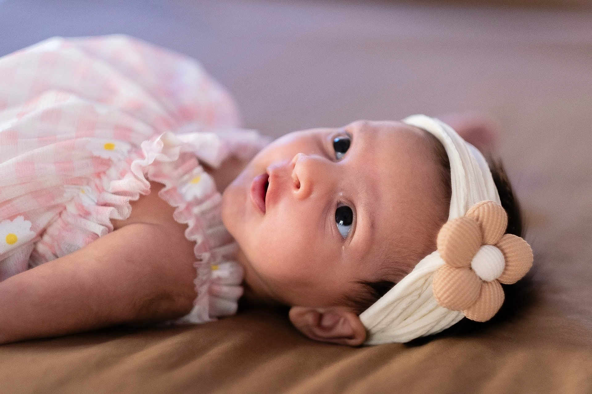 Heera is registered to the contest to win money with this photo: baby, infant, headband, flower, pink_dress, lying_down, close_up, cute, child, portrait, soft_lighting, indoors, skin, face, eyes, young_child, head, apparel, fabric, resting