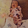 Storii is registered to the contest to win money with this photo: baby, blanket, bows, child, comfort, cozy, cushion, cute_outfit, faces, fur_texture, happy, indoors, infant, laughing, pacifier, person, resting, sleepwear, smiling, soft_lighting