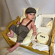 Keid joined the competition — help win amazing prizes! baby, birthday_cake, box, cake, celebration, child, clothing, cushion, cute, face, hat, headwear, indoors, infant, person, portrait, sitting, smiling, suspenders, wooden_cradle