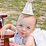 baby, child, party_hat, outdoor, blue_eyes, striped_clothing, wooden_chair, grass, curious_expression, cute, first_birthday, infant, portrait, summer, one_year_old, celebration, hat, person, sitting, daylight