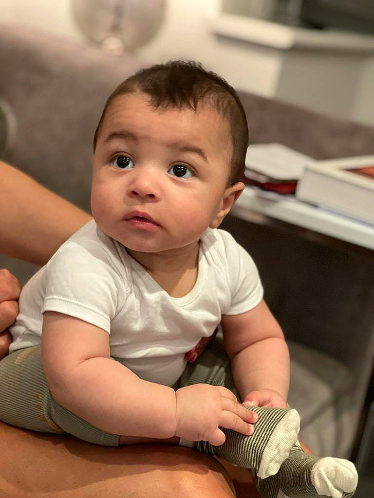 Cruz is registered to the contest to win money with this photo: baby, baby_toddler_clothing, cheek, child, chin, comfort, elbow, flooring, happy, human, human_body, microphone, mouth, nail, nose, organ, person, skin, surprise, thumb