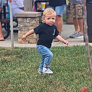 Ryker is registered to the contest to win money with this photo: child, toddler, blond_hair, blue_eyes, outdoor, grass, walking, running, playful, portrait, full_body, black_shirt, blue_jeans, sneakers, crowd, park, sidewalk, stone_pillar, photograph, phone_watermark