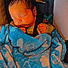 baby, sleeping, infant, portrait, blanket, blue_blanket, floral_pattern, toy, pacifier, chair, indoors, cozy, peaceful, resting, closed_eyes, dark_hair, bundled_up, child, nap, close_up