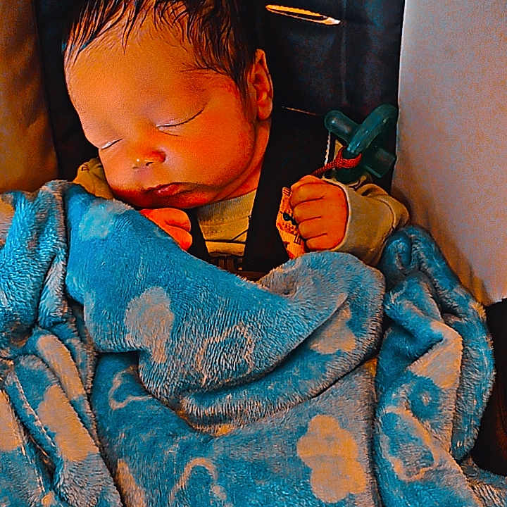 Reason joined the competition — help win amazing prizes! baby, sleeping, infant, portrait, blanket, blue_blanket, floral_pattern, toy, pacifier, chair, indoors, cozy, peaceful, resting, closed_eyes, dark_hair, bundled_up, child, nap, close_up