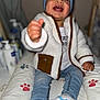 Maë participe au concours pour gagner de l'argent avec cette photo : toddler, child, smiling, jacket, beanie, sneakers, jeans, indoor, cushion, paw_print, happy, clothing, baby, face, person, portrait, seated, hand, footwear, cute