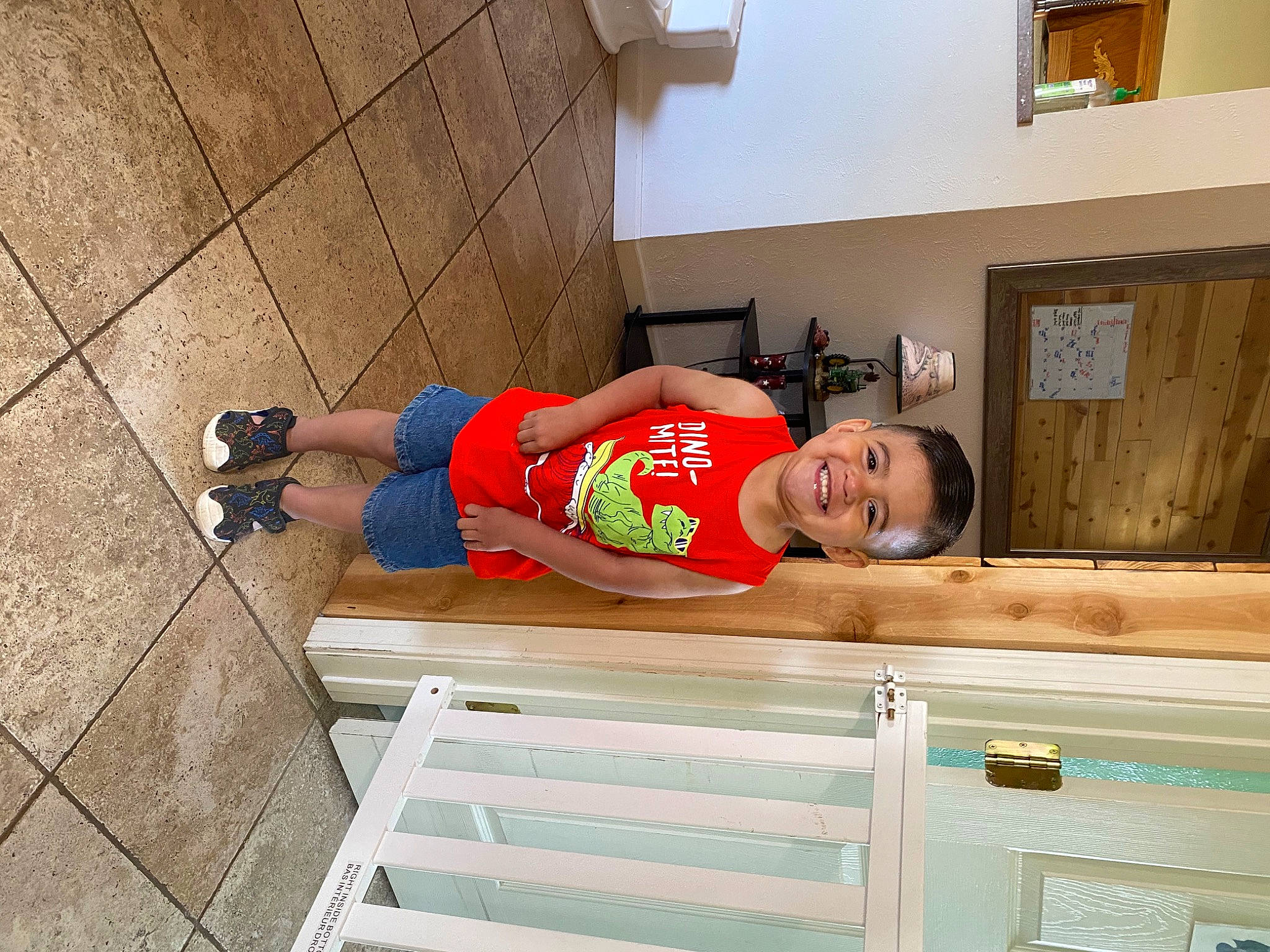 Noah is registered to the contest to win money with this photo: baby_toddler_clothing, child, concrete, floor, flooring, fun, handrail, hardwood, house, human_leg, joy, leg, person, picture_frame, room, shorts, smile, t_shirt, thigh, toddler
