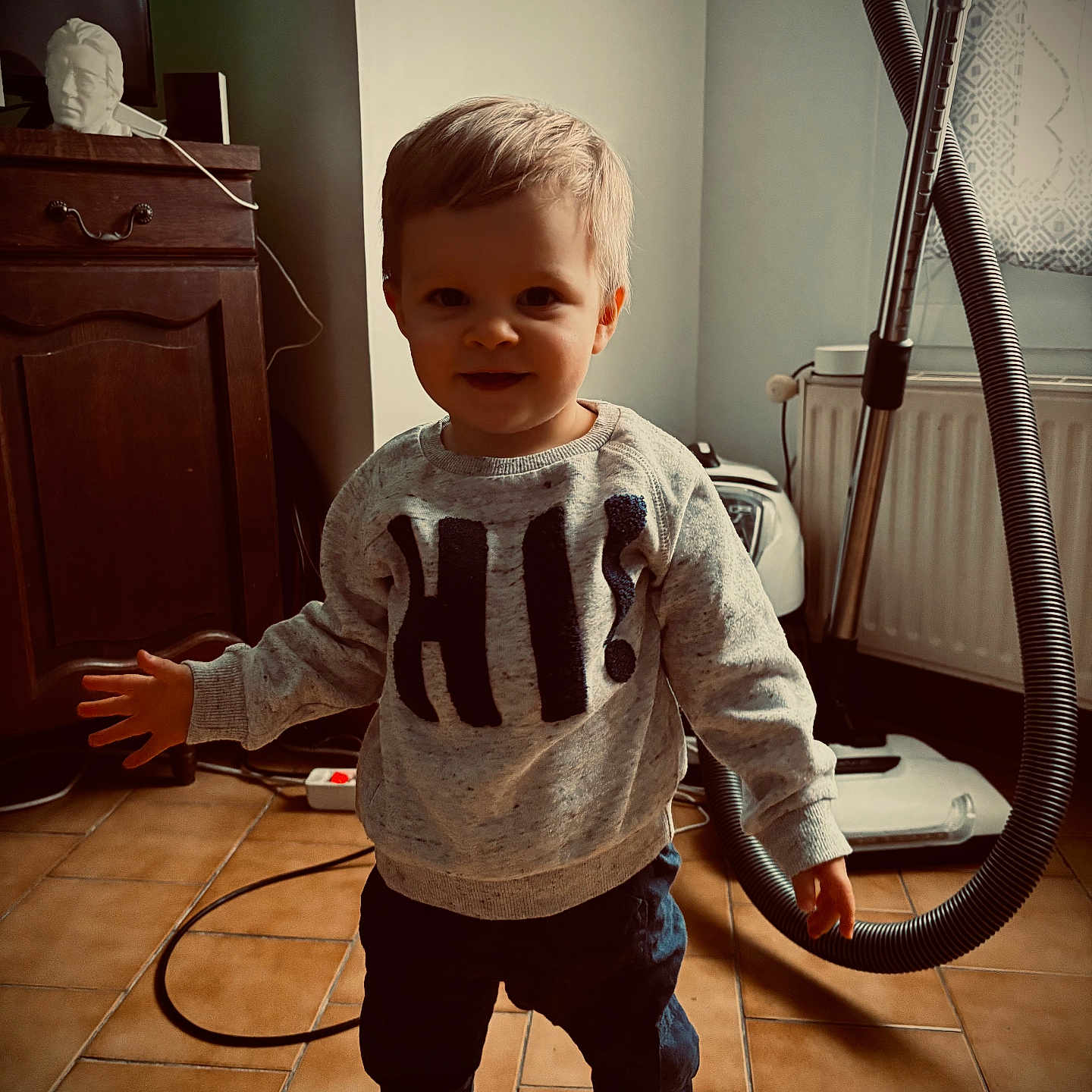 Kenny participe au concours pour gagner de l'argent avec cette photo : cabinet, child, clothing, cord, curtain, face, floor, furniture, hair, hand, indoor, plug_socket, room, smile, standing, sweater, tile_floor, toddler, vacuum_cleaner, window