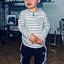 Kenny participe au concours pour gagner de l'argent avec cette photo : toddler, child, indoor, striped_shirt, adidas_pants, sneakers, standing, curious_expression, hands_clasped, floor_tiles, tv_screen, gaming_controller_box, furniture, cables, power_outlet, plastic_bag, home, casual_clothing, young_child, portrait
