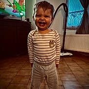 Kenny participe au concours pour gagner de l'argent avec cette photo : toddler, child, smiling, pajamas, striped_clothing, bear_design, indoor, living_room, floor_tiles, vacuum_cleaner, television, curtains, window, radiator, toy, happy, person, young_child, home, cute