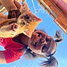 Ginger is registered to the contest to win money with this photo: antenna, blue_sky, building, cat, close_up, cute, hair, hand, happy, kitten, orange_cat, outdoor, person, pet, pigtails, playing, roof, smiling, sunny, young_person