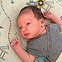 newborn, baby, infant, striped_onesie, blanket, airplane_pattern, clouds, lying_down, face, head, arm, hand, skin, cute, portrait, indoors, soft_light, resting, small_fingers, peaceful