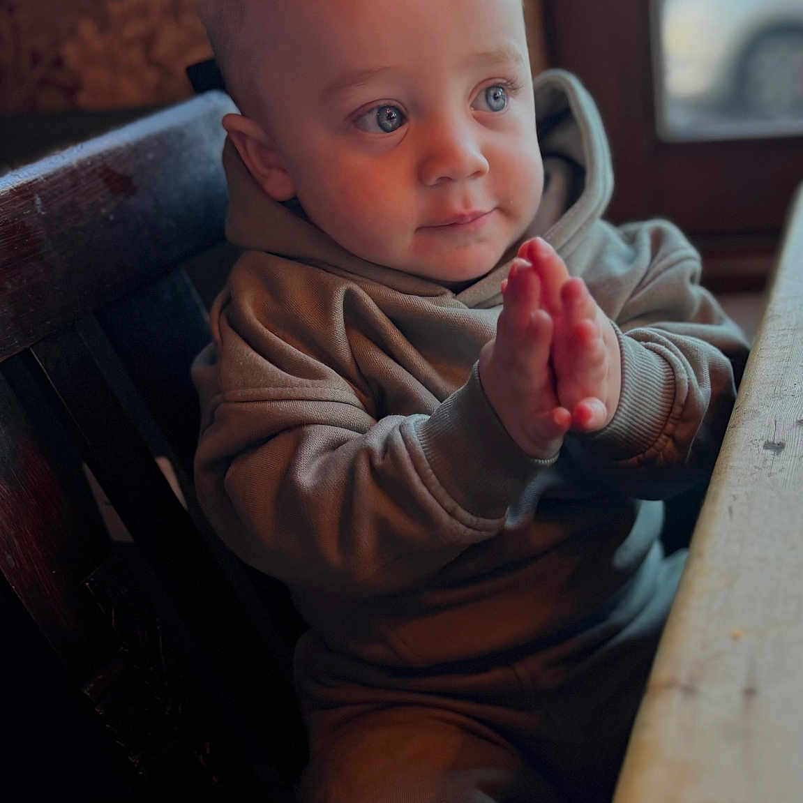 Chester is registered to the contest to win money with this photo: baby, bodypart, clothing, couch, face, finger, furniture, hand, happy, head, hoodie, knitwear, pants, person, photography, portrait, sitting, smile, sweater, wood